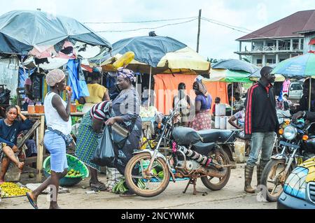 Einkaufen und Verkaufen auf dem geschäftigen Monrovia - Gbarnga Highway. Der Markt ist sehr geschäftig, und die Anbieter nehmen einen Teil der Straße ein, was zu starken Staus führt. Liberia. Stockfoto