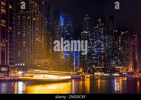 Dubai Marina bei Nacht, beleuchtete Wolkenkratzer und Kanalboote. VAE Stockfoto