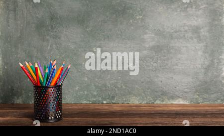 Nahaufnahme einer Bank mit Bleistiften und Stiften auf dem Hintergrund der Schultafel, Kopierraum, zurück zur Schule Stockfoto