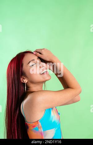 Seitenansicht eines optimistischen jungen asiatischen weiblichen Modells mit farbenfrohem, oben lächelnden Augen vor grünem Hintergrund Stockfoto