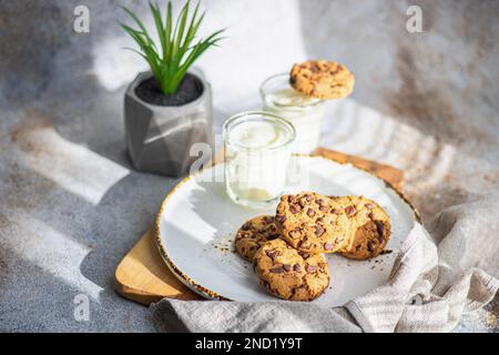 Gesunde Haferkekse mit Schokolade und ein Glas Joghurt auf dem Beton- oder Steintisch Stockfoto