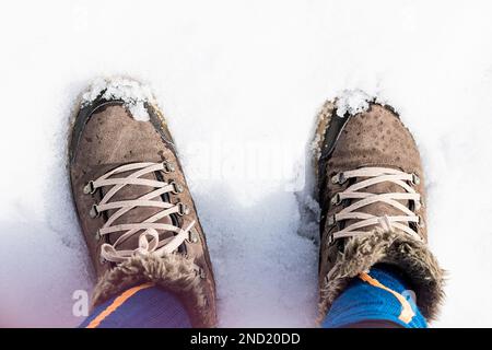 Draufsicht einer unbekannten Person in warmen Stiefeln, die im Winter auf verschneitem Boden steht Stockfoto