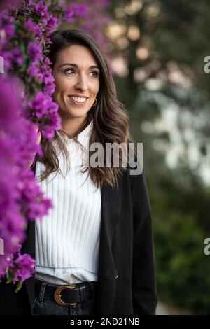 Porträt einer Frau mittleren Alters in der Nähe von violetten Blumen Stockfoto