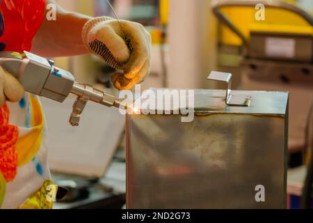 Nahaufnahme: Schweißer Hände mit Handlaserschweißmaschine Stockfoto