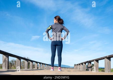 Rückansicht einer Läuferin mit den Händen auf der Hüfte in Ruhe. Stockfoto