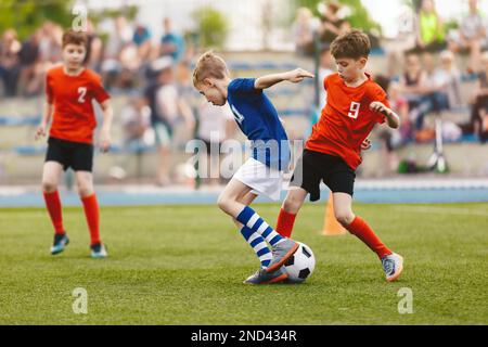 Eine Gruppe kleiner Jungs, die Fußball spielen. Fußballspiel zwischen Jugendfußballmannschaften. Junior-Wettkampf zwischen Spielern, die laufen und treten Stockfoto