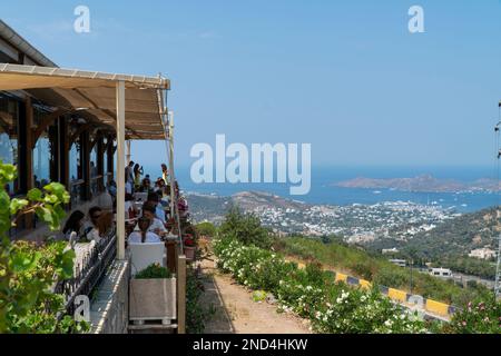 Blick von der Spitze des Hügels Bodrum City, selektiver Fokus. Leute sitzen im Cafe - Restaurant, frühstücken und genießen Bodrum, Türkei Stockfoto