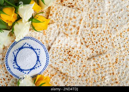 Das Konzept der Pessachstunde. Matzah, roter Koscher, weiße und gelbe Rosen und Walnuss. Traditionelles jüdisches Brot Matzah, Kippah und Talllit auf Alt Stockfoto