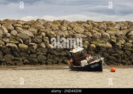 Fischerboot, das bei Ebbe in Rhos-on-Sea vom Wellenbrecher geschützt ist Stockfoto