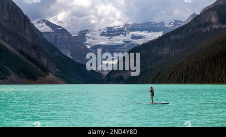 Eine junge kanadierin, die auf dem Lake Louise im Banff National Park, Kanada, Stand-Up-Paddleboarden macht. Stockfoto