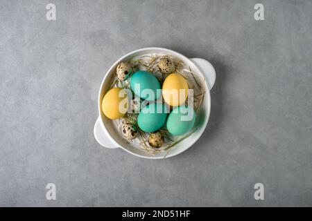 Bunte Hühnereier und Wachteleier in einem weißen Gericht Stockfoto