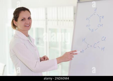 Eine glückliche Frau schreibt eine chemische Formel auf ein Whiteboard Stockfoto