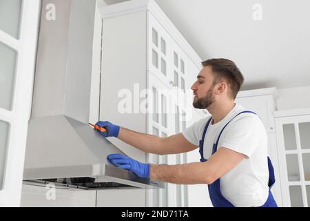 Arbeiter, der moderne Dunstabzugshaube in der Küche repariert Stockfoto