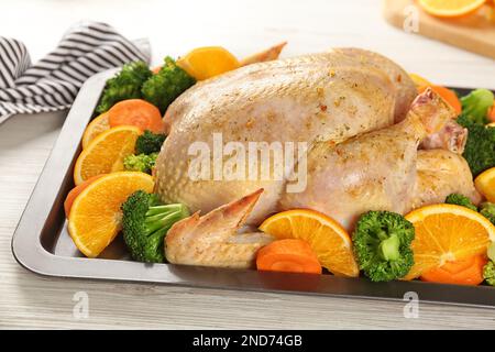 Rohes Hähnchen mit Orangen und Gemüse auf weißem Holztisch, Nahaufnahme Stockfoto