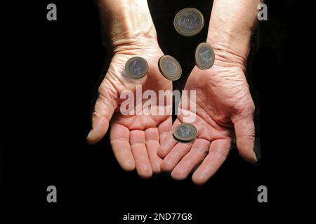 Geld fällt in offene Hände auf schwarzem Hintergrund. Das Konzept eines Schattengeschäfts. Stockfoto