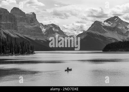 Ein einsamer Abenteurer auf einer Kanufahrt in Schwarz und Weiß auf dem Maligne Lake, den kanadischen Rockies, dem Jasper-Nationalpark, Alberta, Kanada. Stockfoto