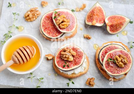 Bruschetta mit frischem Ricotta, Feigen, Nüsse, Thymian und Honig auf grauem Beton Hintergrund. Stockfoto