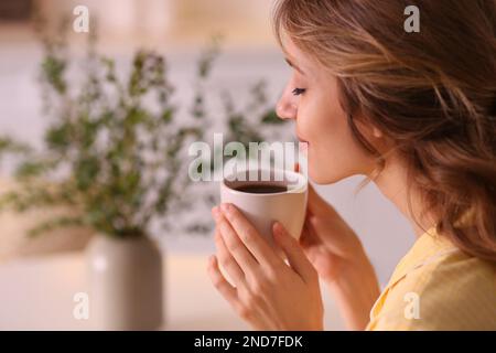 Schöne junge Frau, die zu Hause Kaffee trinkt. Wochenendmorgen Stockfoto