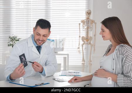 Gynäkologe, der Schwangeren in der Klinik Ultraschallbilder vorstellt Stockfoto