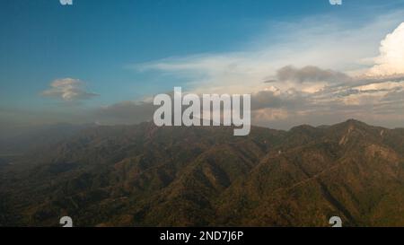 Blick von oben auf den Sonnenuntergang in den Bergen vor dem blauen Himmel und den Wolken. Philippinen. Stockfoto