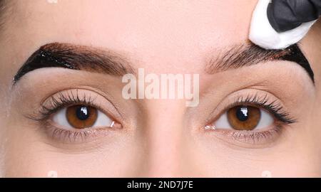 Kosmetikerin, die die Augenbrauen einer Frau auf weißem Hintergrund abwischte, Nahaufnahme Stockfoto