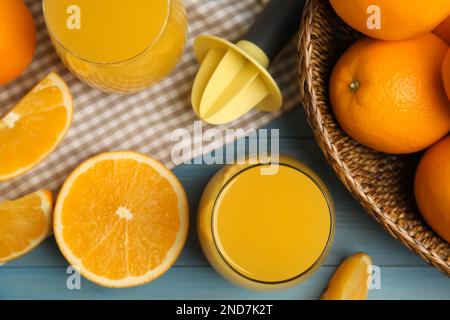 Frisch zubereiteter Saft, Orangen und Reibahle auf blauem Holztisch, flach liegend Stockfoto