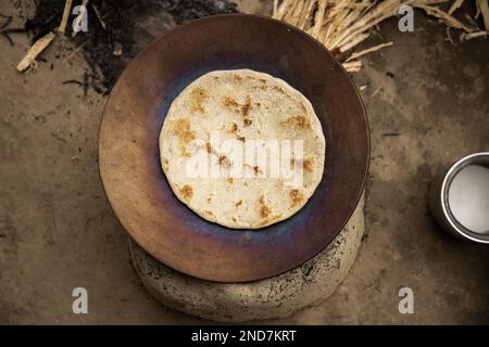 Der Blick von oben auf ein indisches Brot wird auf dem traditionellen Schlammherd/Chulah in einem Dorf in Indien zubereitet Stockfoto