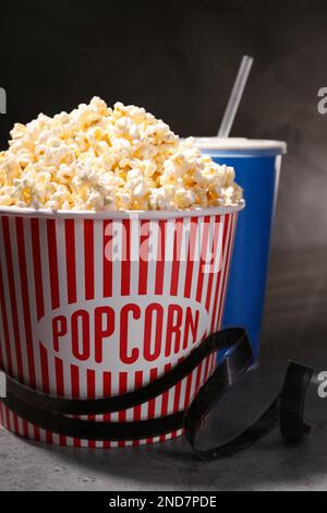 Köstliches Popcorn, Getränk und Klebeband auf grauem Tisch Stockfoto