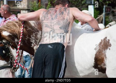 Der Reiter auf der Appleby Horse Fair zeigt seine Appleby- und Pferdetattoos auf dem Rücken. Stockfoto