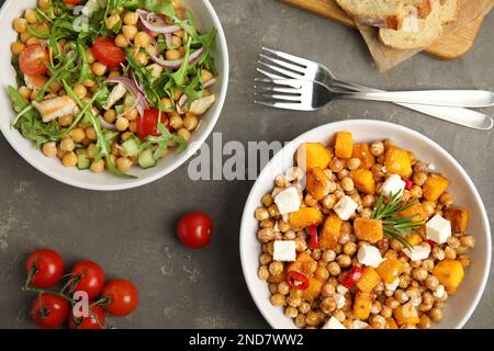 Leckere frische Kichererbsensalate auf grauem Tisch, flach liegend Stockfoto