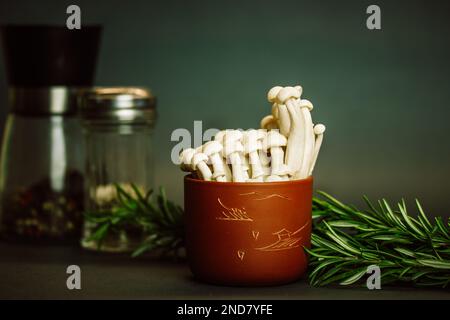 Frische rohe weiße Shimiji-Shimeji-Pilze in brauner Schüssel Hypsizygus tessulatus Asia-Pilze. Vegetarische vegane asiatische gesunde Lebensmittel. Buche-Pilzrücken Stockfoto