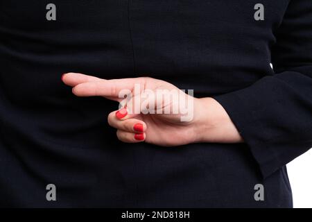 Nahaufnahme einer erwachsenen Geschäftsfrau in formeller Kleidung, die Pech-Gesten macht, mit gedrückten Daumen hinter dem Rücken, als Unternehmenskonzept isoliert auf weißem Studio B. Stockfoto