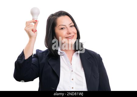 Eine glückliche Unternehmerin in trägt einen eleganten, lässigen Anzug und ein weißes Hemd, das eine Glühbirne in der Hand hält, als gute Idee isoliert im Studiohintergrund Stockfoto