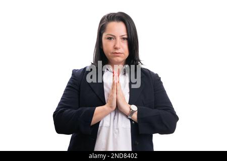 Erwachsene Geschäftsfrau mit ernsten Gesichtsausdrücken, die formelle Kleidung trägt und die Hände als Gebete oder dankbare Geste auf weißen s aneinander hält Stockfoto