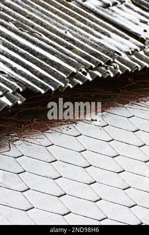 Der Rand von zwei Dächern mit verschiedenen Beschichtungen, die mit frischem Schnee bedeckt sind. Selektiver Fokus Stockfoto