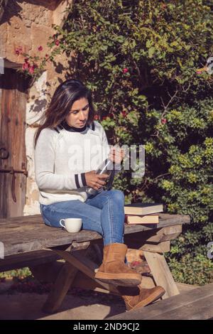 Frau gießt eine Tasse Tee aus der Thermoskanne, draußen, Stockfoto