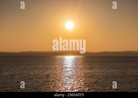 Wunderschöner Sonnenuntergang über dem atemberaubenden Gardasee in Italien, mit der Sonne, die auf dem ruhigen Wasser reflektiert, und einer friedlichen Atmosphäre. Perfekt für Trav Stockfoto