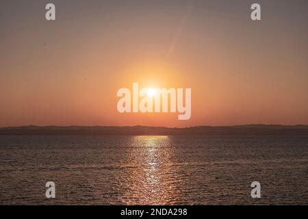 Wunderschöner Sonnenuntergang über dem atemberaubenden Gardasee in Italien, mit der Sonne, die auf dem ruhigen Wasser reflektiert, und einer friedlichen Atmosphäre. Perfekt für Trav Stockfoto