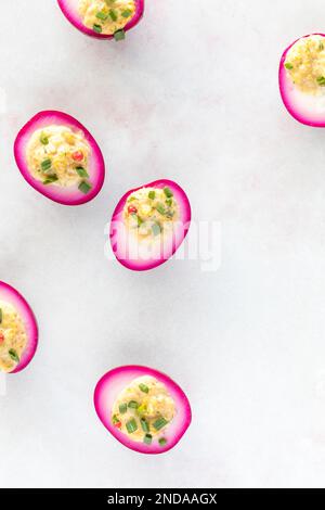 Blick von oben auf leuchtend rosaftgefärbte Eier auf einer hellen Oberfläche. Stockfoto