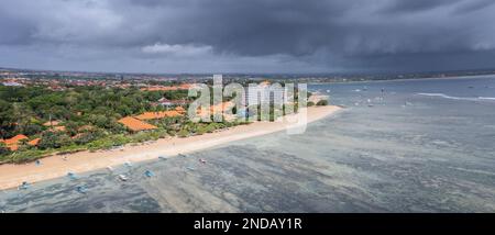 Malerischer Panoramablick am Anfang des Sanur-Strandes mit breiter, sehr flacher Küste, dunkle, schwere Wolken vor Regen, Bali, Indonesien Stockfoto