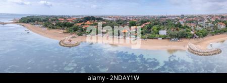 Malerischer Panoramablick aus der Vogelperspektive auf den südlichen Teil von Sanur Beach mit breiter, sehr flacher Küste, dunklen, schweren Wolken vor Regen, Bali, Indonesien Stockfoto