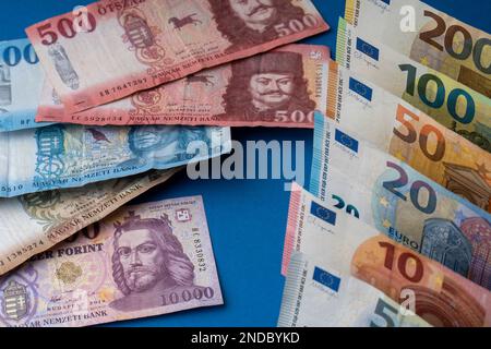 Ungarische Forint und 10-, 20-, 50-, 100-, 200-Euro-Banknoten werden auf eine Ebene Oberfläche gelegt. EUR-Wechselkurs HUF. Stockfoto