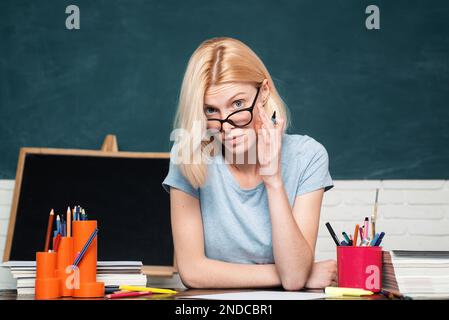 College-Student auf dem Campus. Porträt einer lächelnden Schülerin oder Lehrerin auf grünem Hintergrund an der Tafel. Danke, Herr Lehrer. Stockfoto