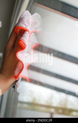 Nahaufnahme der Hand einer Frau beim Reinigen eines Fensterglases, keine Handschuhe, Frühjahrsputz. Hochwertiges Foto Stockfoto