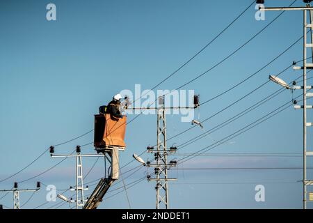 Elektroarbeiter stellen eine Hochspannungsverbindung her. Strommasten und -Kabel. Stockfoto