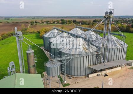 Landwirtschaftliche Silos auf dem Hof im Herbst, Nahaufnahme der Drohne. Industriekörner, Aufzugtrockner, Gebäudeaußenseite, Lagerung und Trocknung von Getreide Stockfoto