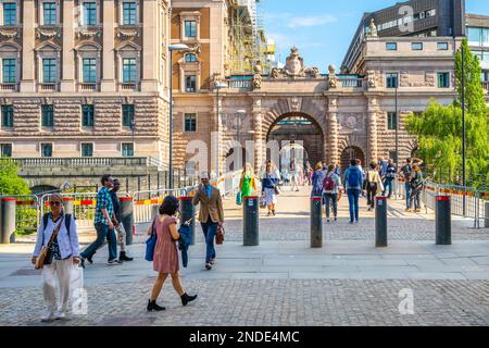 STOCKHOLM, SCHWEDEN - 10. JUNI 2022: Menschen, die in den Straßen von Stockholm durch das Parlamentsgebäude gehen, Schwedisch: Riksdagshuset, Gate, Stockholm, Schweden Stockfoto