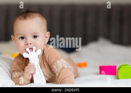 Baby bis zu einem Jahr, liegt auf dem Bett zwischen Spielzeug Stockfoto