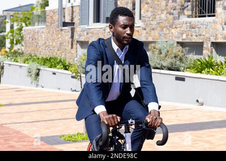 Ein afroamerikanischer Geschäftsmann, der Anzug trägt und mit der Tasche zur Arbeit fährt Stockfoto