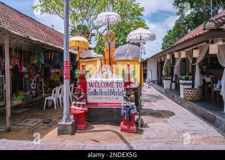 Willkommen auf dem Sindhu Beach Market in Sanur Bali Nachricht am Eingang, Begrüßung mit zwei Dämonenwachen Statuen im traditionellen balinesischen Stil Stockfoto
